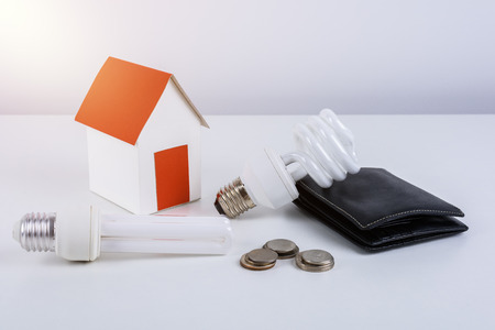 Energy savings lamp with wallet and coins, paper house model. Energy Saving Ideas and Save Money Concept For the homeの写真素材