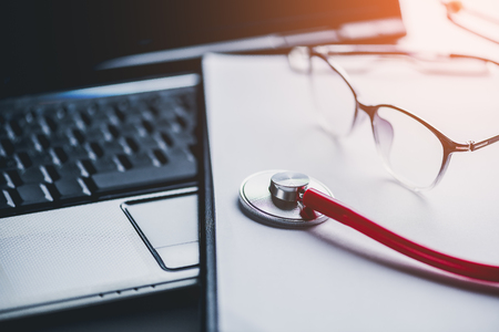 stethoscope and glasses on laptop with clipboard blank paper doctor online, medical conceptの写真素材