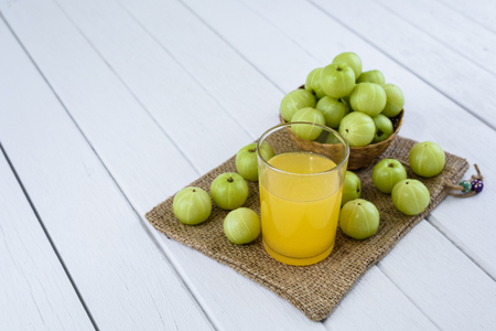 Indian gooseberry in Wicker basket and juice, Sackcloth on white wooden tableの写真素材