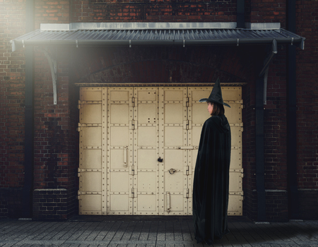Portrait of woman in black Scary witch halloween costume with Old Brick Wall of the Ancient Castle of the Witch is background Vintage style Colorの写真素材