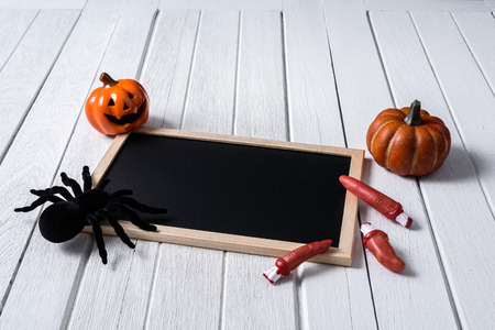halloween background with Pumpkins, black spider and empty chalkboard on white wooden floorの写真素材