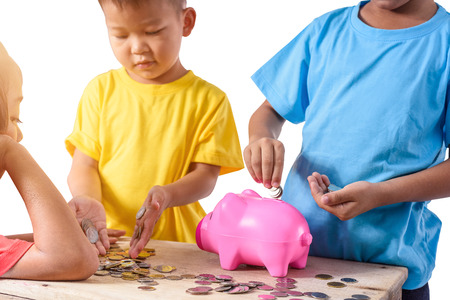 Group of asian children are helping putting coins into piggy bank on white background. Education Savings conceptsの写真素材