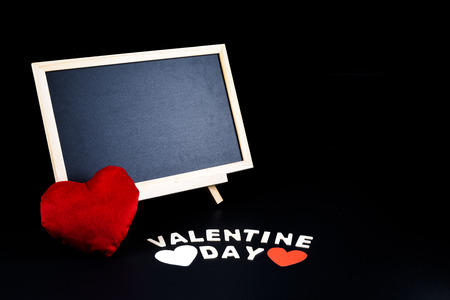 Empty Chalkboard on stand, Heart shape and Wooden letters word "VALENTINE DAY" on black background. Concept of Valentine's dayの写真素材