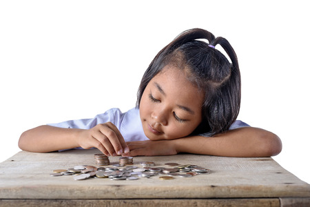 Cute asian girl in school uniform counting and pile coins for saving isolated on white background with clipping path. Education Savings conceptsの写真素材