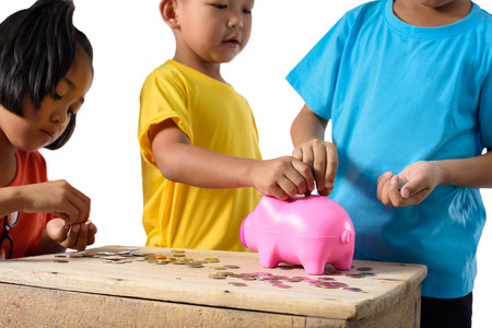 Group of asian children are helping putting coins into piggy bank isolated on white background with clipping path. Education Savings conceptsの写真素材