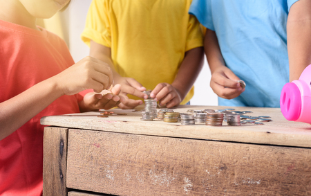 Hands of asian children are helping putting coins into piggy bank on white background. Education Savings conceptsの写真素材