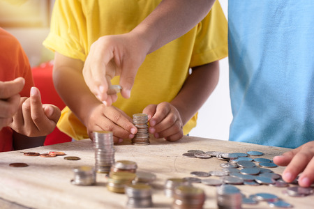 Hands of asian children are helping putting coins into piggy bank \ on white background. Education Savings conceptsの写真素材