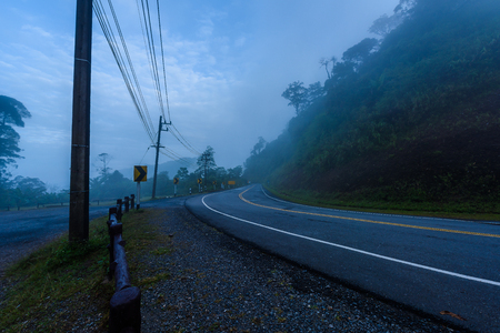 Curve road signs on down hill. Many warning sign indicating for safety at Viewpoint "1715" Doi Phu Kha National Park, Nan Province, Thailand. in the morning with fogの写真素材