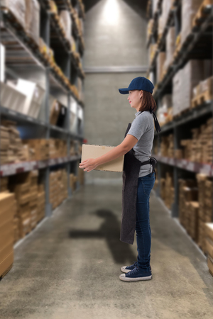 Female staff Lifting parcel boxes with Blurred the background of the warehouseの写真素材