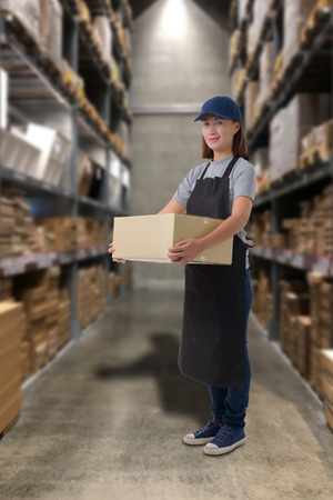 Female staff Lifting parcel boxes with Blurred the background of the warehouseの写真素材