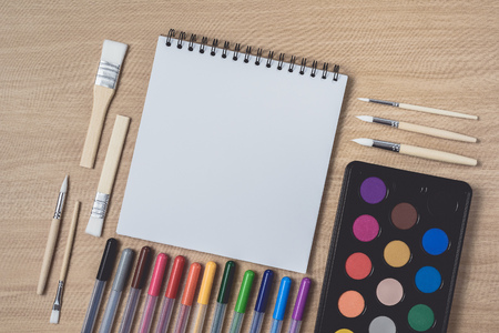 Notepad or notebook with Many colorful pens, paintbrush and Watercolor palette on brown wood table.using for Arts and Education background. Take note on book with paper and concept, copy space for your textの写真素材