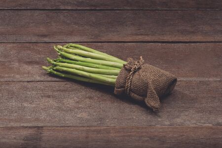 Fresh Asparagus in Sack bag on wooden table. Customize retro style imagesの写真素材