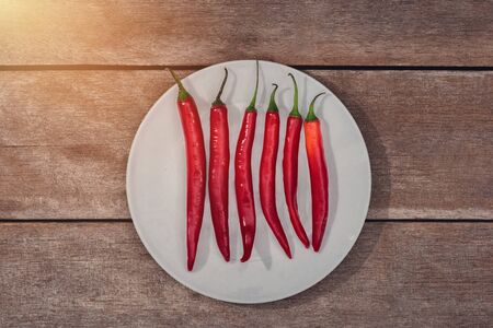 Red chili in white plate on wooden table background. Customize retro style imagesの写真素材