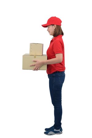 Smiling delivery woman in red uniform giving parcel boxes, isolated on white background with clipping path. delivery service, mail, logistics, people and shipping courier service conceptの写真素材
