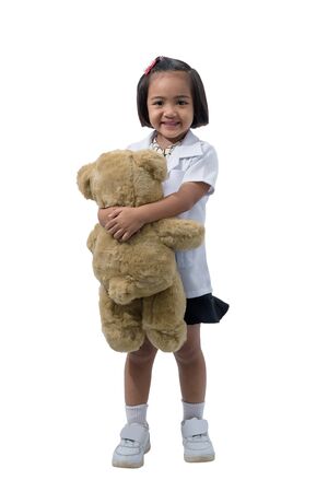 Cute Little asian girl doctor smiling while wearing Doctor's uniform Carrying a teddy bear. Standing isolated on white background with clipping pathの写真素材