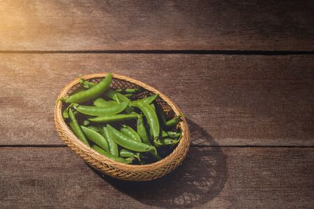 Fresh green peas or beans in basket on wooden table. Customize retro style imagesの写真素材