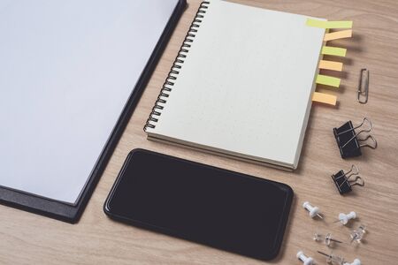Workspace with diary or notebook and smart phone, clipboard, pencil, sticky notes on wooden background. Flat lay, top view office table desk and copyspaceの写真素材