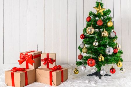 Christmas tree and ornaments with gifts boxes on white fur and white wooden background with copy spaceの写真素材
