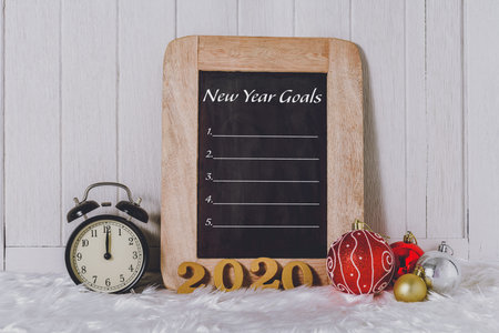 2020 wooden text with Alarm clock with Christmas ornaments and New Year's Goals List written on...