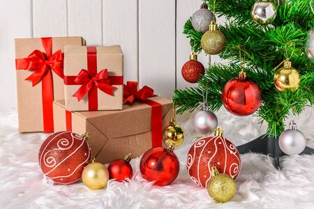 Close up Christmas tree and ornaments with gifts boxes on white fur and white wooden backgroundの写真素材