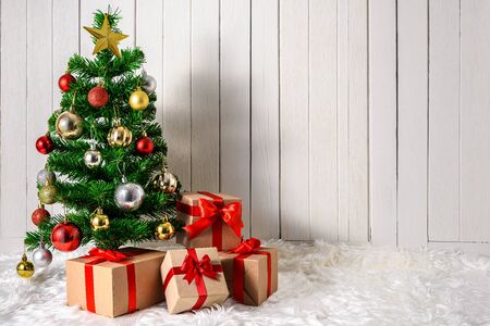 Christmas tree and ornaments with gifts boxes on white fur and white wooden background with copy spaceの写真素材