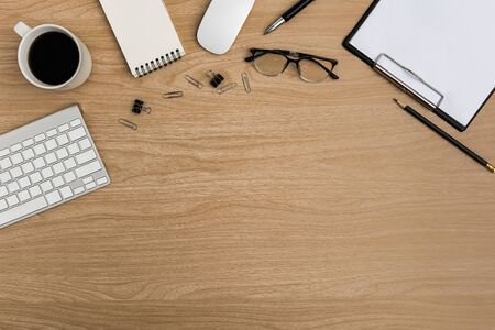Top view Wood office desk table. Flat lay Workspace with eye glasses, keyboard, mouse computer, paper clip, clipboard, notebook, pencil, pen, coffee cup office supplies on wooden backgroundの写真素材