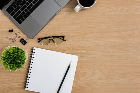 Top view Wood office desk table. Flat lay Workspace with coffee cup, tree pot, laptop, notebook, pen, paper clip office supplies on wooden table backgroundの写真素材