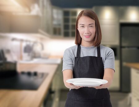 Female Chef assistant or housewife holding Kitchen equipment and blurred background kitchenの写真素材