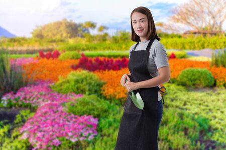 Portrait of Female gardener hand holding shovel and blurred background is flower gardenの写真素材