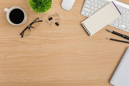 Top view Wood office desk table. Flat lay Workspace with eye glasses, coffee cup, tree pot, keyboard, mouse computer, paper clip, notebook, pencil, pen office supplies on wooden backgroundの写真素材