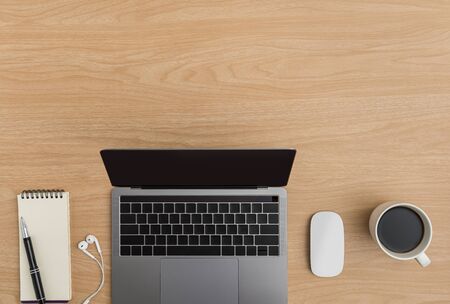 Top view Wood office desk table. Flat lay Workspace with earphone, laptop, mouse computer, coffee cup, notebook, pen office supplies on wooden backgroundの写真素材