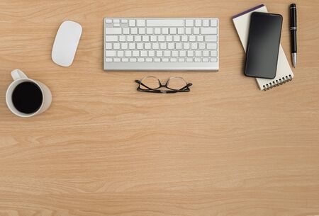 Top view Wood office desk table. Flat lay Workspace with eye glasses, keyboard, mouse computer, notebook, pen, coffee cup, smart phone office supplies on wooden table backgroundの写真素材