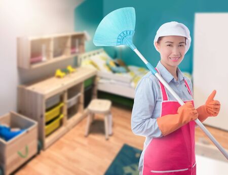 Cleaning concept Woman with bucket of washing fluids and rags in hands and cleaning equipment ready to clean house on blurred bedroom backgroundの写真素材