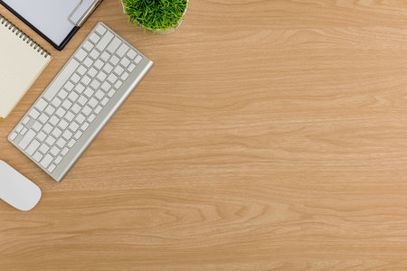 Top view Wood office desk table. Flat lay Workspace with tree pot, keyboard, mouse computer, notebook office supplies on wooden backgroundの写真素材