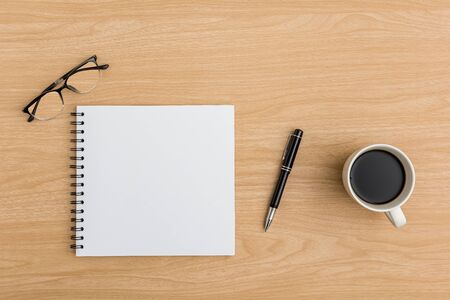 Top view Wood office desk table. Flat lay Workspace with notebook, coffee cup, eye glasses, pen office supplies on wooden table backgroundの写真素材