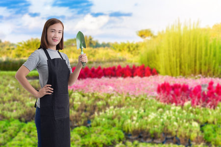 Portrait of Female gardener hand holding shovel and blurred background is flower gardenの写真素材