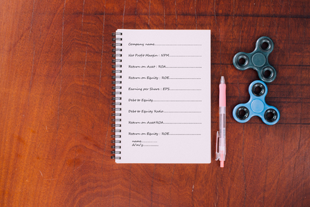 Pen, Black and blue hand spinner at the top notebook on wood table background,The notebook had vocabulary about business.の写真素材
