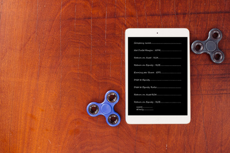 Black and blue hand spinner, The tablet had vocabulary about business on wood table backgroundの写真素材