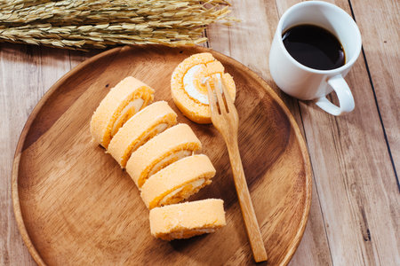 Breakfast set, Homemade orange swiss cake roll  and black coffee in white cup, Right side had wheat...