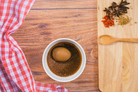 hard-boiled eggs in the sweet gravy with chinese five spice stew and wood spoon on wooden table, Right side had wheat cereal grain,Napkin on right sideの写真素材