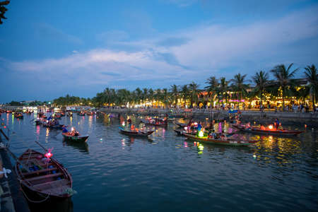 Hoi an classic city in vietnam at night with coloured lanterns light reflecting on the river and a wooden boat on the river.のeditorial素材