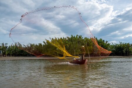 Hunting for Sunset. Silhouette of fisherman throwing fishing net into the river,vietnam.の写真素材