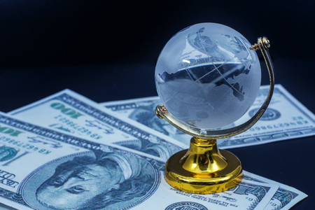 Glass globe model gold stand on  money black table backgroundの写真素材