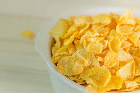 The image  Close up Cornflakes cereal breakfast in white bowl on wooden table.