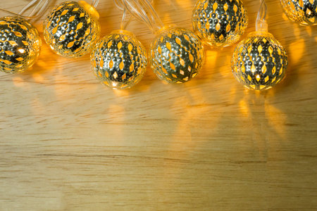 The Christmas gold lights ball decor on wood table.