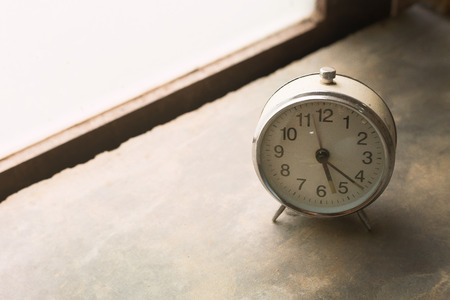 The white vintage clock alarm  near window light.の写真素材
