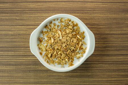 A Morning food almond flakes  and milk in white bowl on wood table.の写真素材