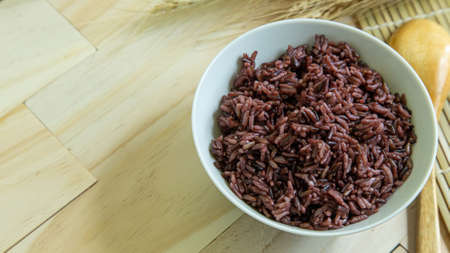 The Riceberry in white bowl on wood table for health food contentの写真素材