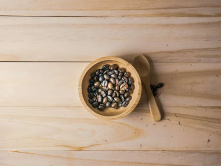 The coffee beans in  wood bowl top view on wooden table for food content.の写真素材