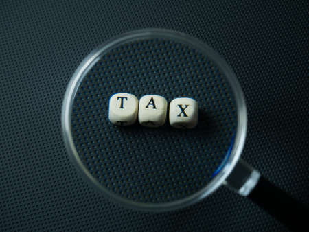 Magnifying glass and tax wood cube for business contentの写真素材